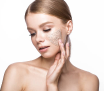 Woman applying face scrub to her face against a white background