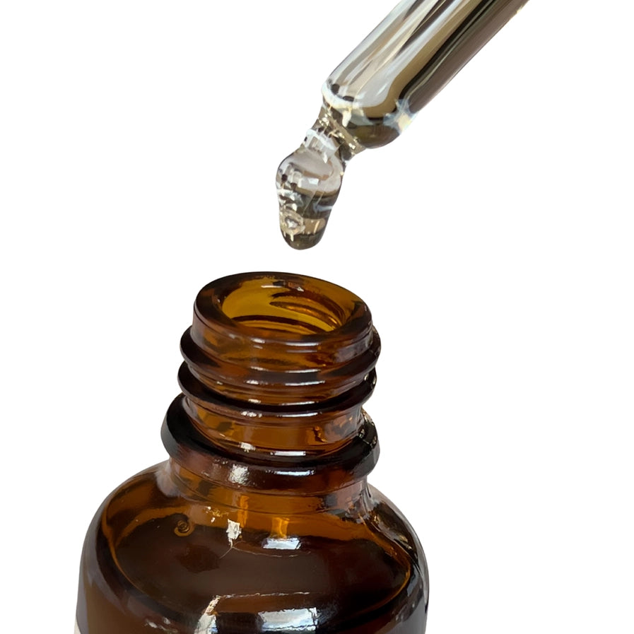 Brown glass dropper bottle with clear liquid on a white background, lid off, liquid drop.