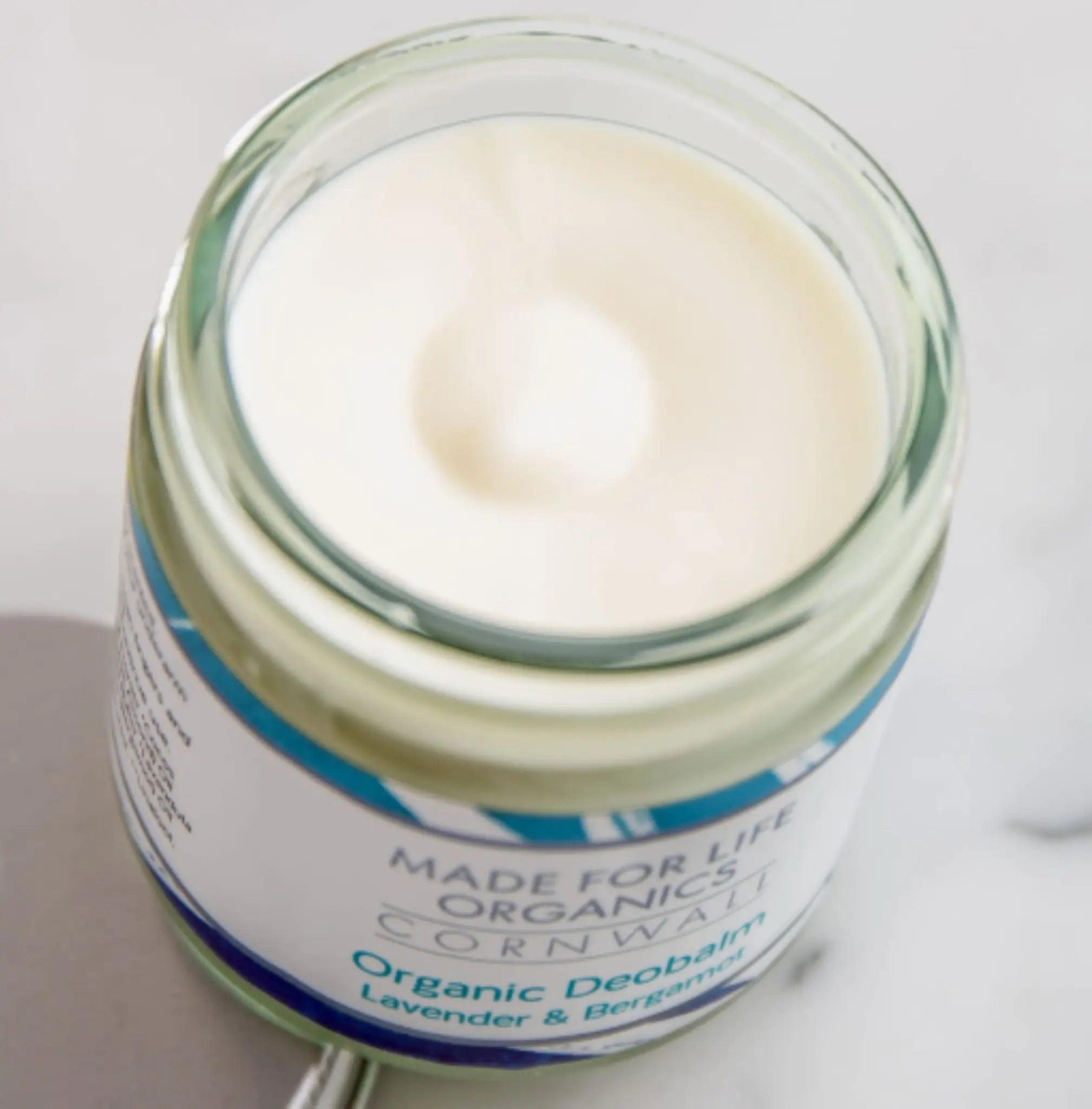 Open Jar with cream-texture natural deodorant. Made for life organics natural deodorant with visible brand label on a neutral background