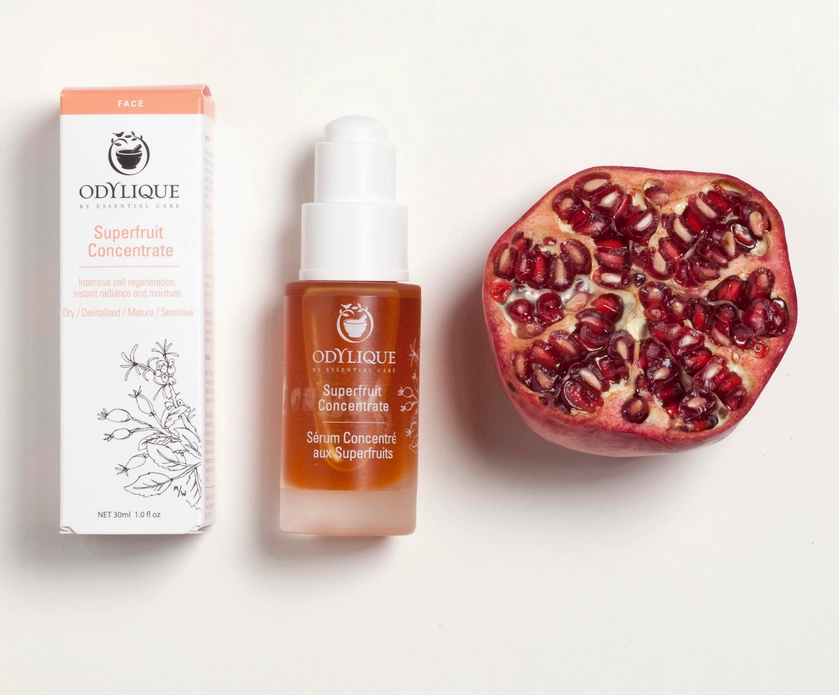 Odylique Superfruit Concentrate serum bottle and packaging on a white background with pomegranate and box.