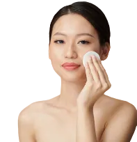 Woman applying face toner with a cotton pad on a white background