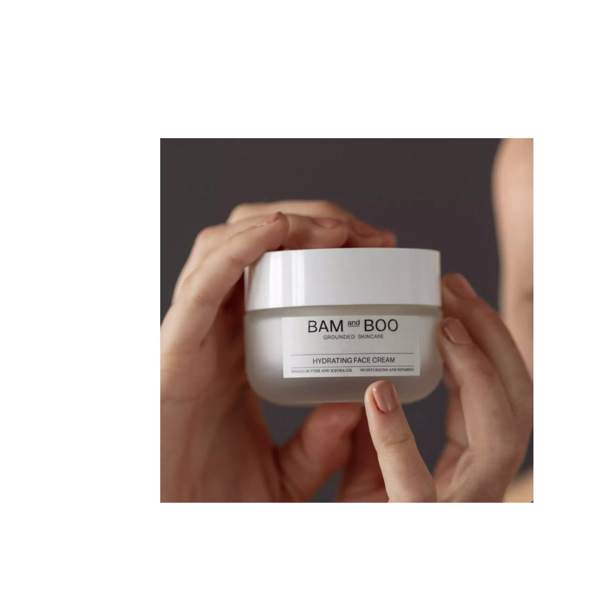 Hand holding a jar of Bam Boo hydrating face cream against a neutral background