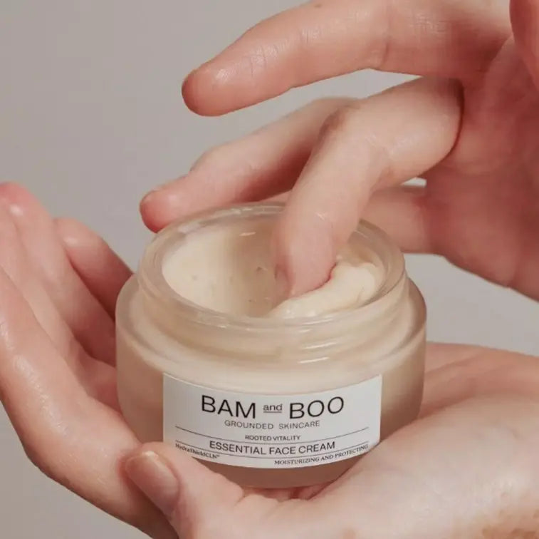 Person applying cream from a jar labeled 'BAM and BOO' on a neutral background
