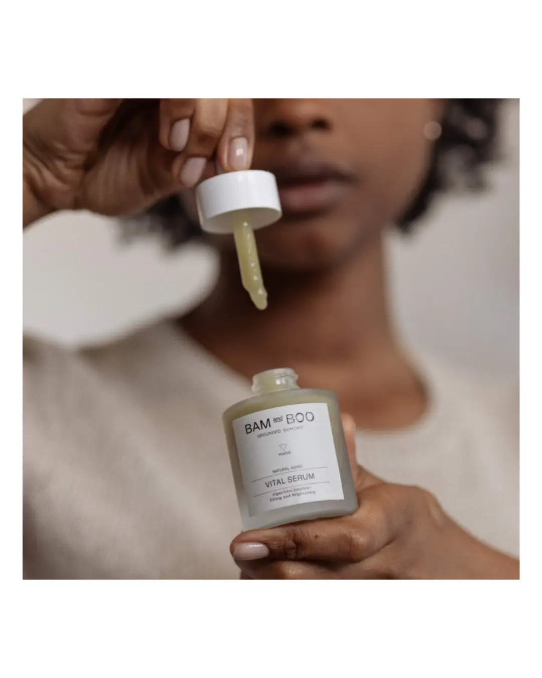 Person holding a bottle of BAMBOO skincare product with a dropper.
