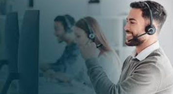 Man wearing a headset in an office setting with colleagues in the background