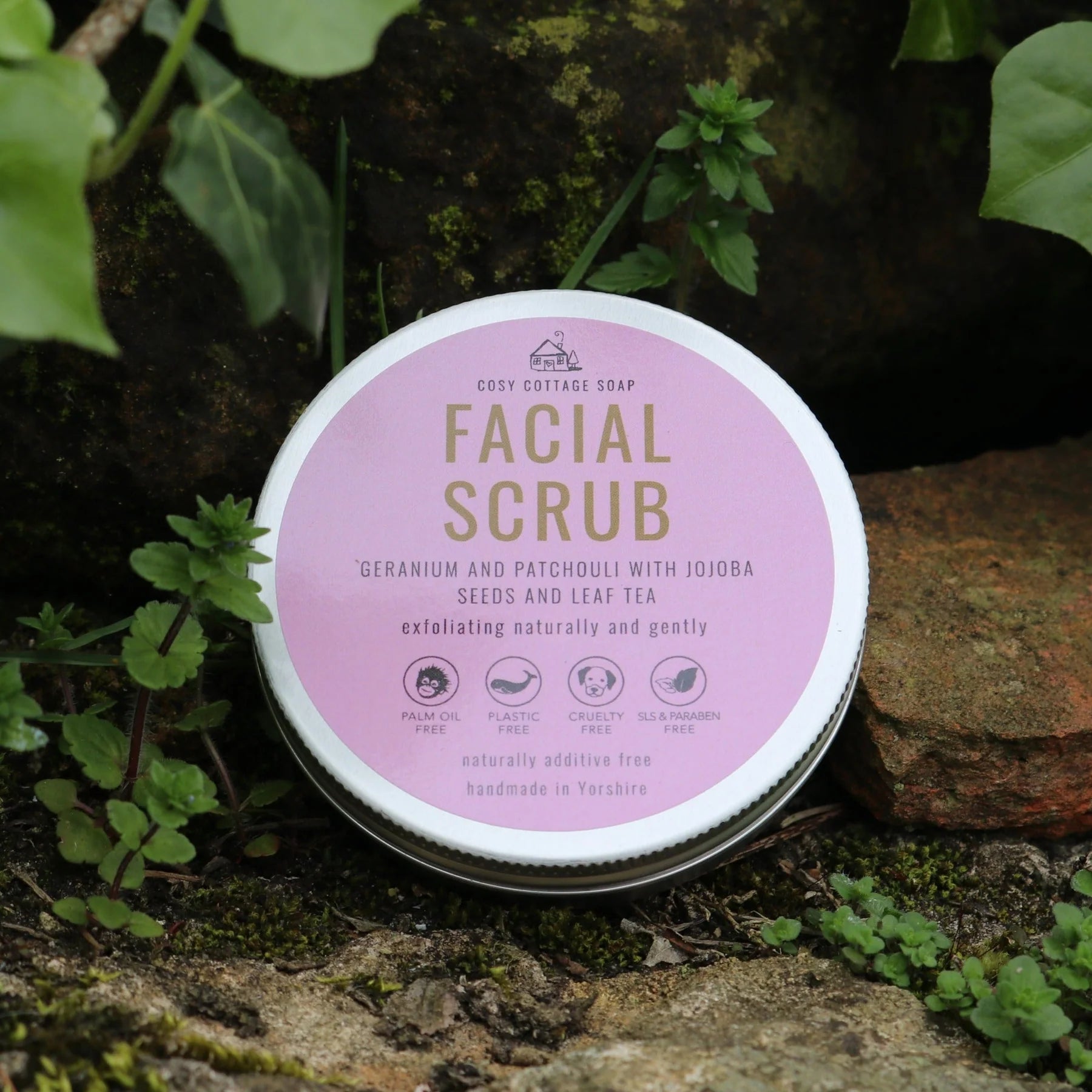 Facial scrub container with pink label on a natural background