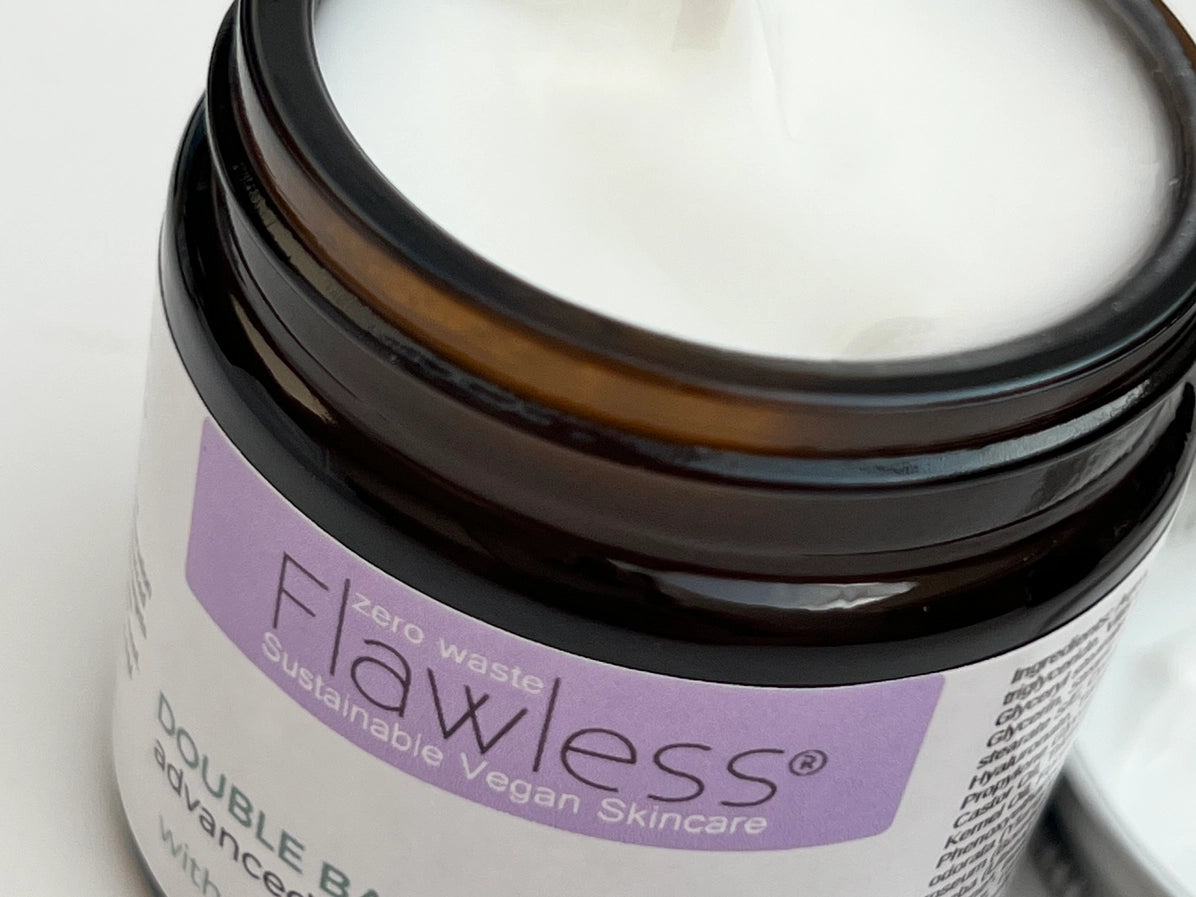 Jar of Flawless skincare product with a purple label on a white background, lid off. top