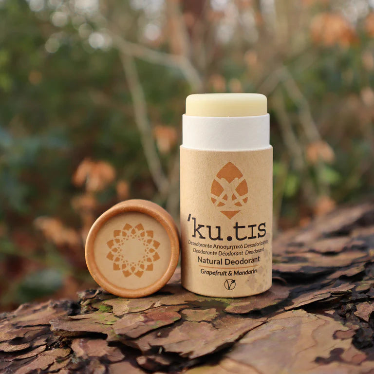 Kutis natural deodorant with awards on a grassy background, lid off, front, yellow cap.