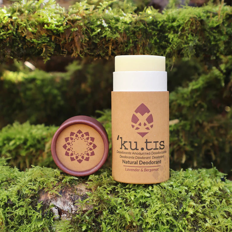 Kutis natural deodorant with a gold award badge on a grassy background, lid off, front view, brown lid
