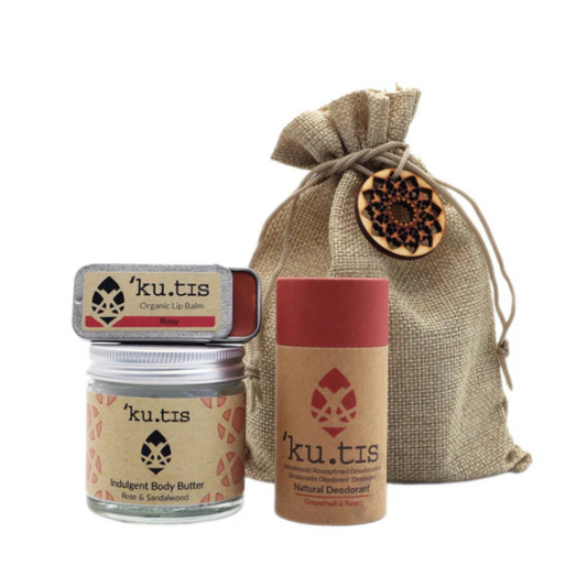 Kutis skincare products including lip balm, body butter, and deodorant with a drawstring bag on a white background.